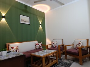 A room with a green wall, two wall-mounted lights, a sofa, two armchairs, a small table with a plant, and a framed picture. - Fantastic 1-bedroom apartment with AC in sunny Hurghada (Hurghada)