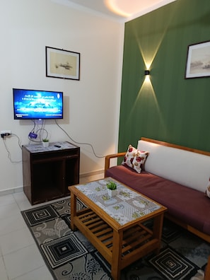 A living room with a television, a sofa, a coffee table, and a wall-mounted light fixture. - Fantastic 1-bedroom apartment with AC in sunny Hurghada (Hurghada)