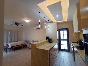 Eine moderne Küche mit einer zentralen Kochinsel, einem Essbereich mit Tisch und Stühlen sowie einem Deckenventilator.