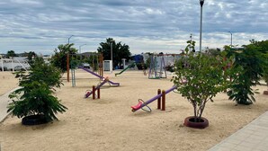 Ein Spielplatz mit Sand, Schaukeln und einer Straßenlaterne.