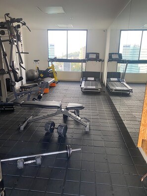 A gym with exercise equipment, a treadmill, and a large window with a city view. - Luxury Loft w/Private Jacuzzi & City Views - El Poblado  (Medellín)