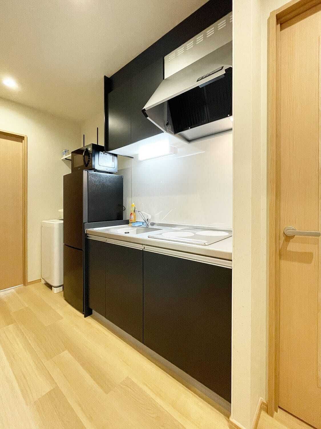 Cocina compacta con microondas, estufa y lavabo.