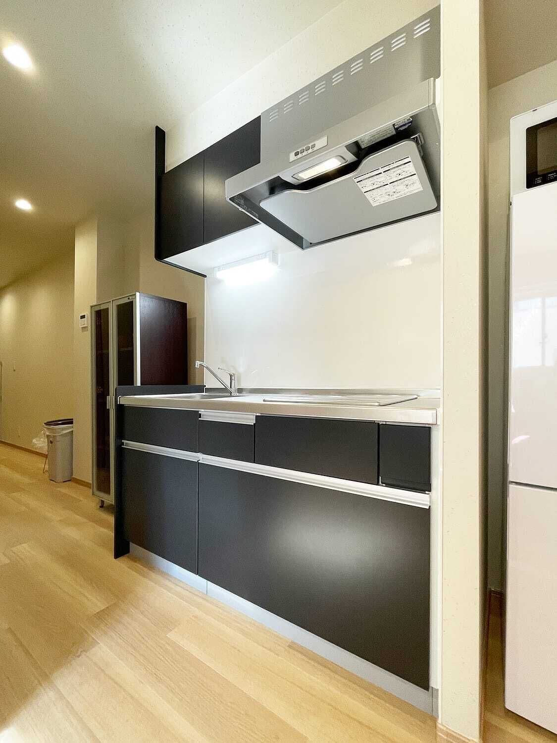 A modern kitchen with a built-in oven, a stainless steel sink, and a white refrigerator.