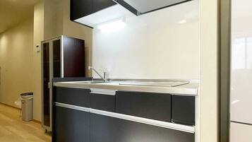 A modern kitchen with a built-in oven, a stainless steel sink, and a white refrigerator.