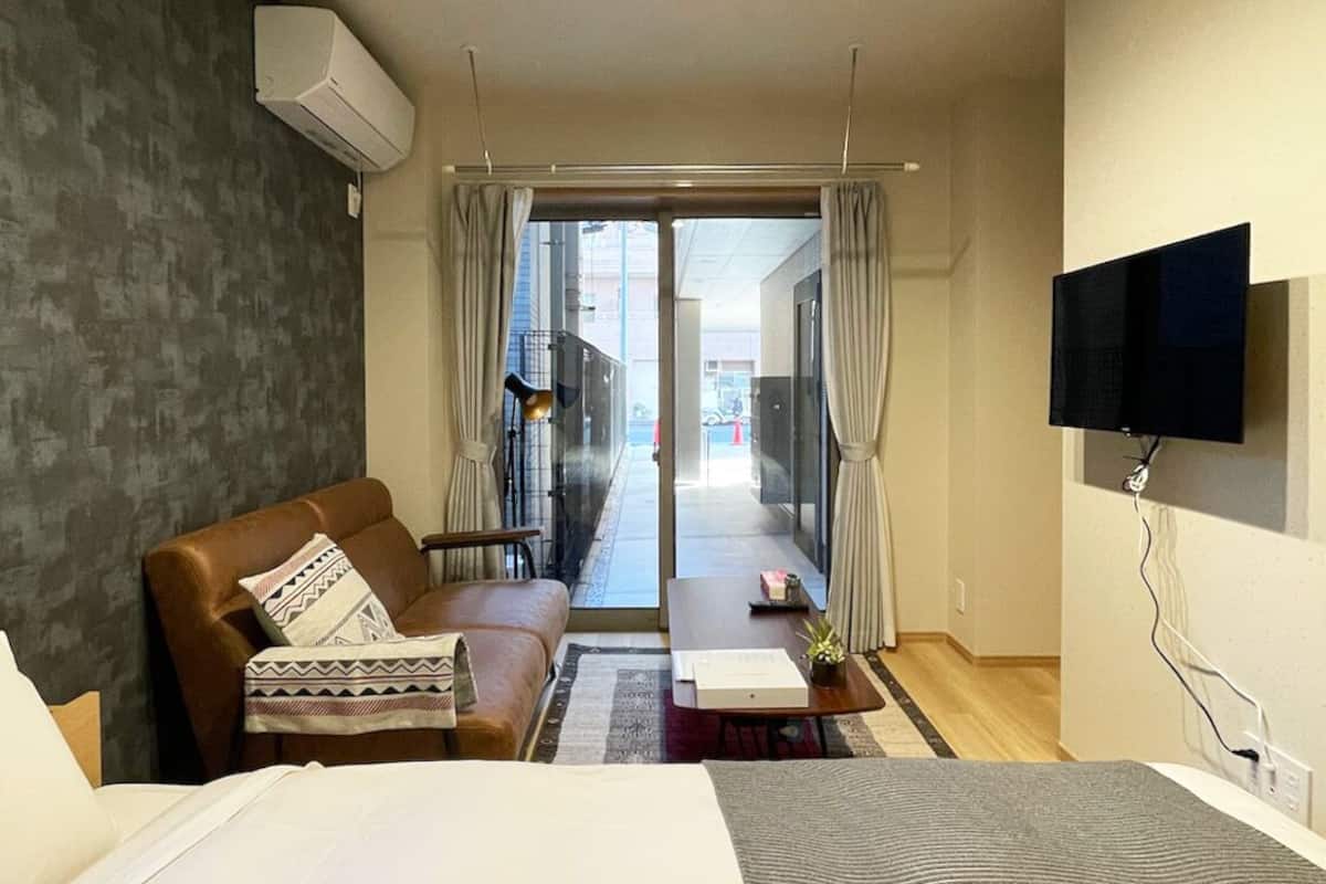 Una habitación de hotel con cama, sofá, televisión y vistas al exterior.