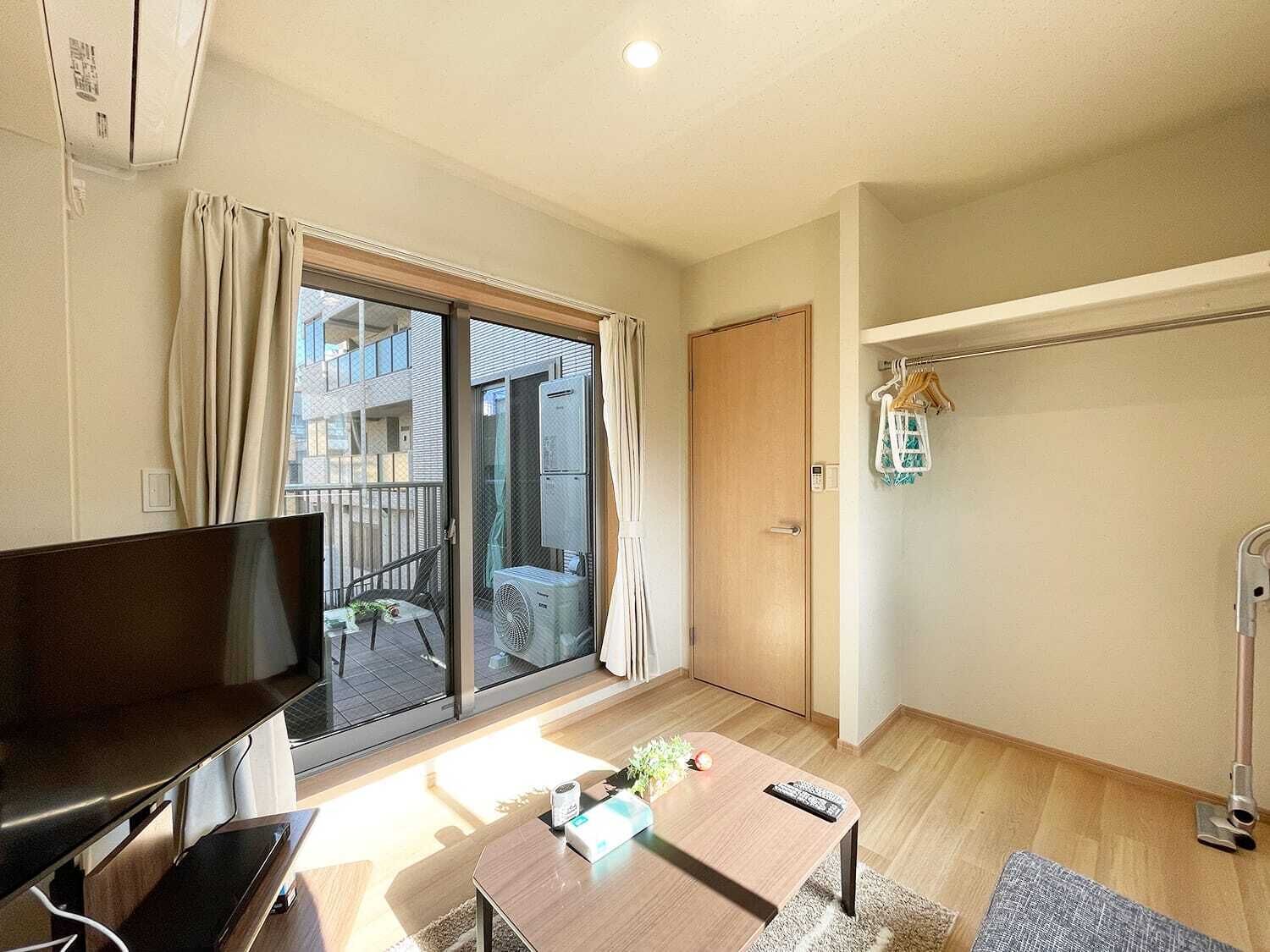 En moderne stue med et fladskærms-tv, et træsofabord og en skydedør til en balkon.