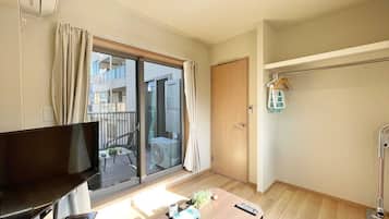 En moderne stue med et fladskærms-tv, et træsofabord og en skydedør til en balkon.
