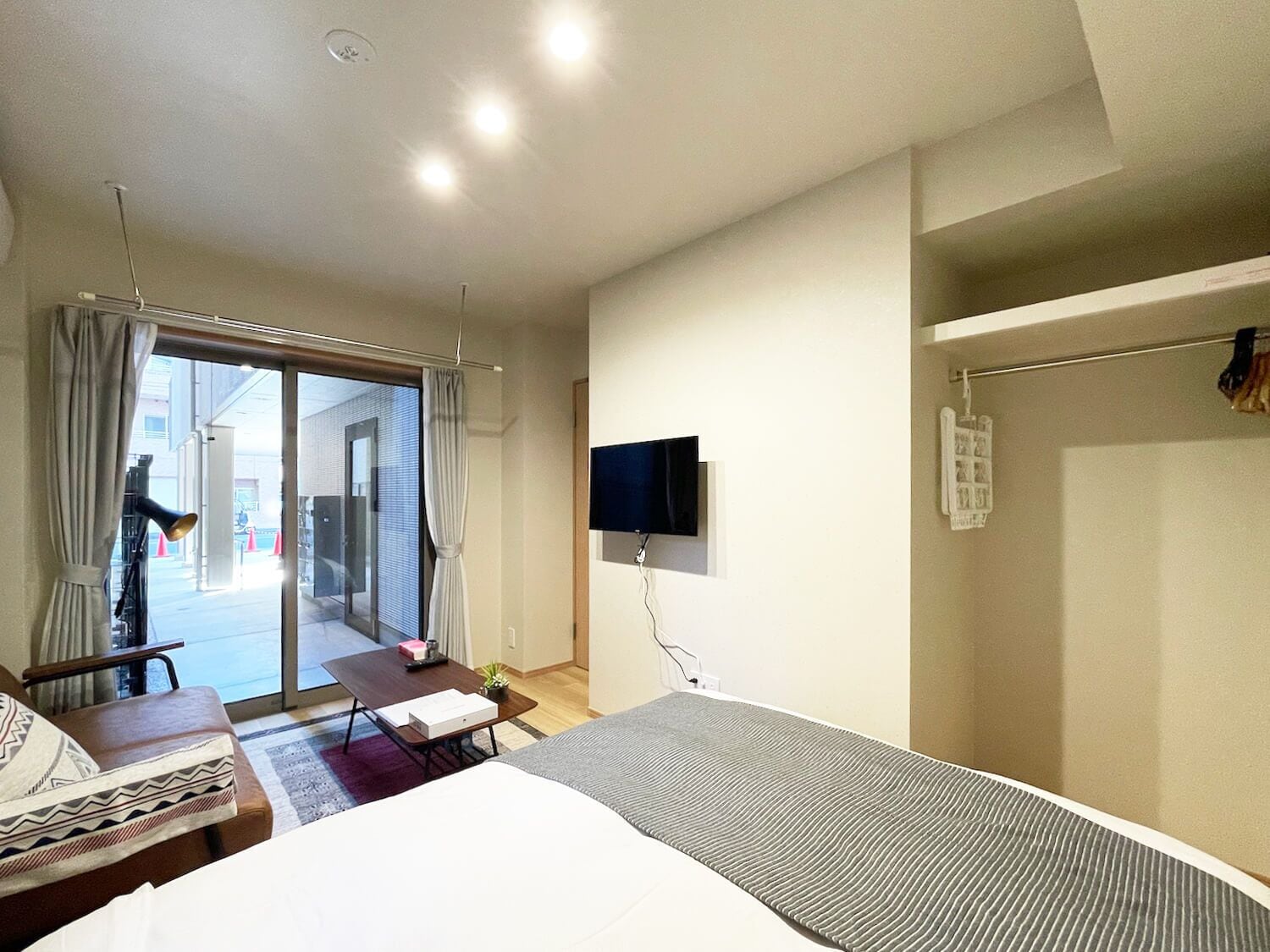 Hotelkamer met een bed, bureau, televisie en een schuifdeur naar een buitenruimte.