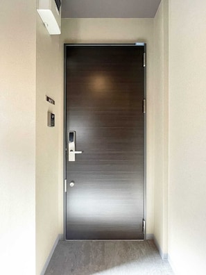 A modern, metallic door with a keypad lock, a small sign above it, and a carpeted floor.
