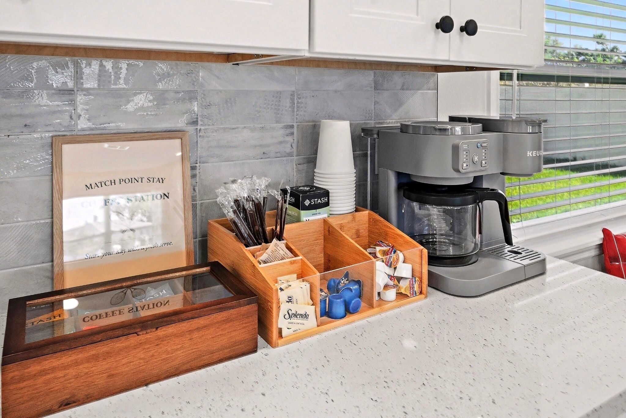 A kitchen counter with a coffee maker, a framed sign, and a wooden organizer with compartments.