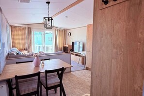 A modern living room with a dining area, a fireplace, a TV, and a large window with curtains. - 3-Bed - Sleeps 6 - Parking - Balcony (Malton)