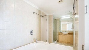 A modern bathroom with a large bathtub, a glass shower enclosure, and a wooden vanity with a sink. - 1 Bedroom Balcony Poolside (Kings Beach)