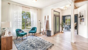 Ett rum med trägolv, en blå stol, en vit lampa och ett fönster med tunna, genomskinliga gardiner.