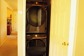 A laundry room with stacked washers and dryers, a door, and a hallway leading to a living area. - Cozy mountain condo on family run ski resort, hiking, biking and more.  (Richmond)