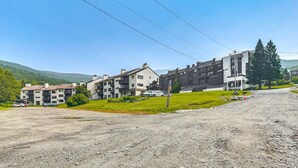 A residential area with multi-story buildings, a gravel driveway, and a grassy area with a few trees.