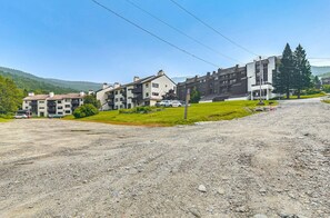 A residential area with multi-story buildings, a gravel driveway, and a grassy area with a few trees.