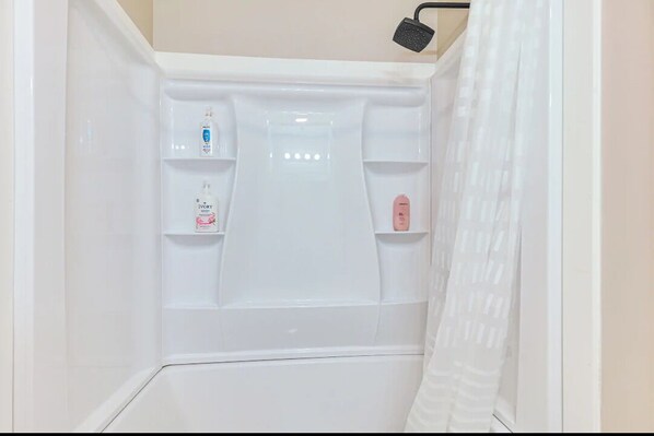 A shower with a handheld showerhead, a soap dispenser, and a shampoo bottle. - Cozy mountain condo on family run ski resort, hiking, biking and more. (Richmond)