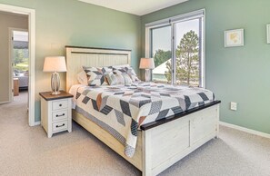 A bedroom with a bed, bedside tables, a window, and a view of the outdoors.