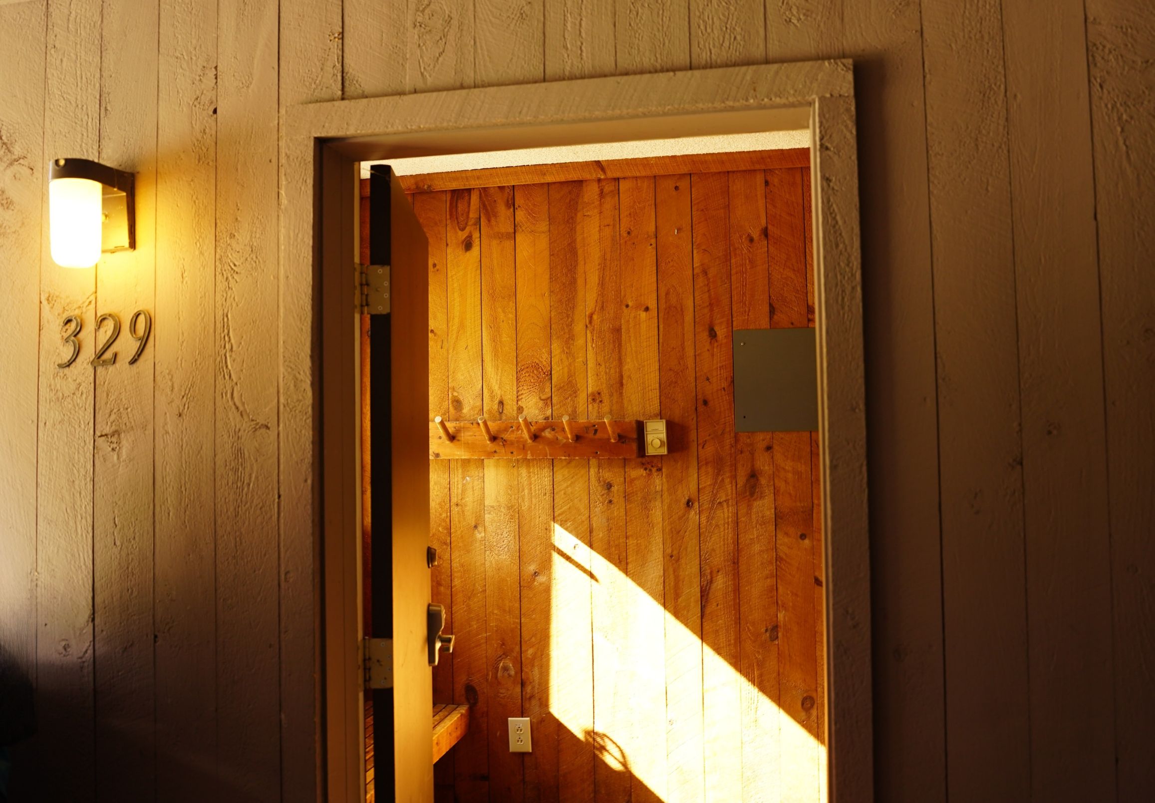 Puerta de madera con el número 329 y un aplique en la pared.