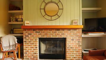 Una sala de estar con chimenea de ladrillo, televisión y un rincón de descanso acogedor.