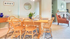 A dining area with a wooden table and chairs, a potted plant, and a mirror on the wall.