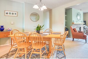 A dining area with a wooden table and chairs, a potted plant, and a mirror on the wall.