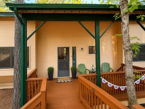 A wooden deck with a covered area, potted plants, and outdoor furniture.
