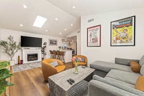 A modern living room with a fireplace, sofas, a coffee table, and a flat-screen TV. - Laurel Canyon Modern 2BR-2BA Cottage-Monthly Stay, Remote Work, Hollywood Hills (Los Angeles)