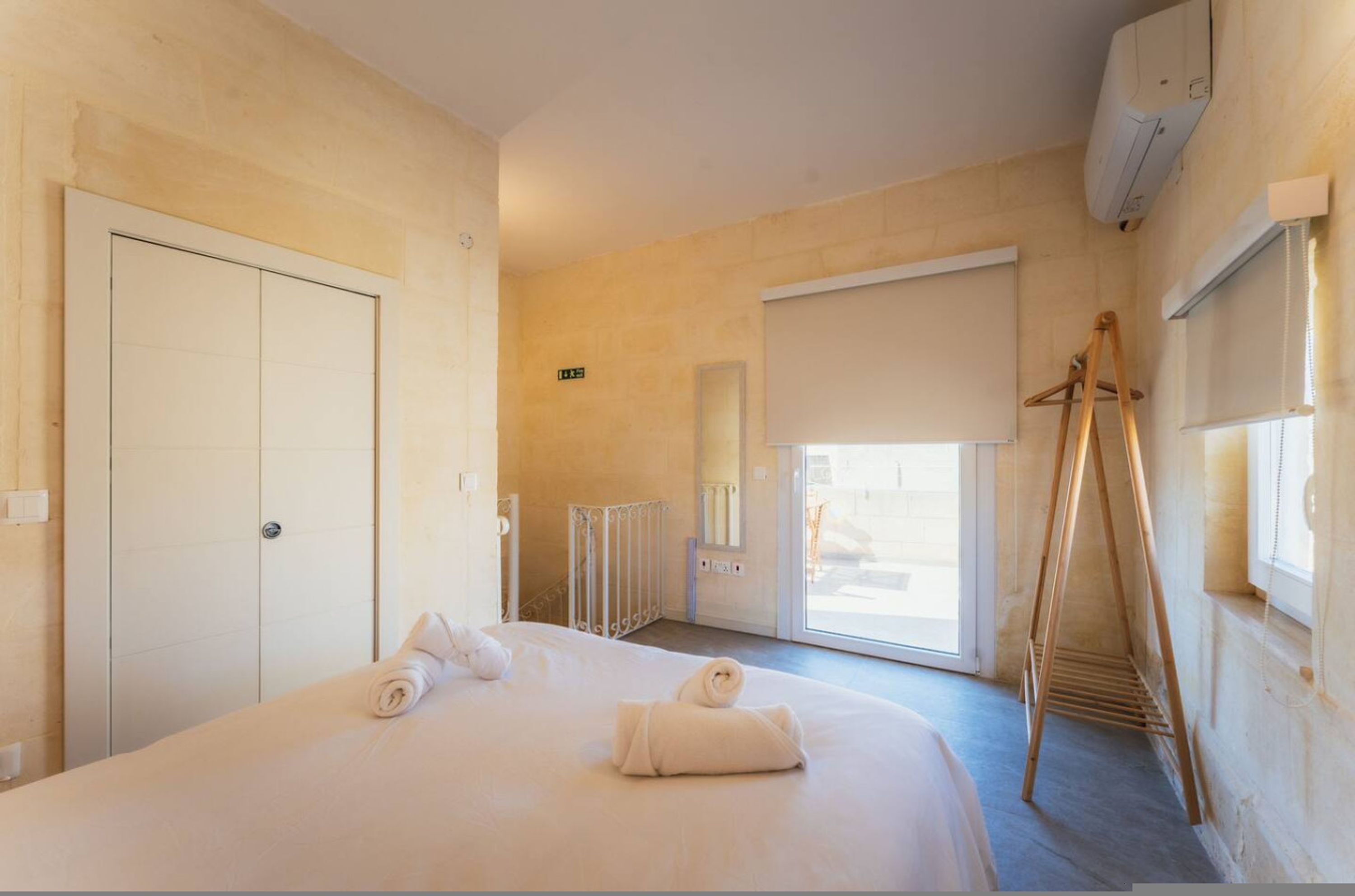 Une chambre d’hôtel avec un lit, une armoire, un radiateur, une fenêtre et un balcon.
