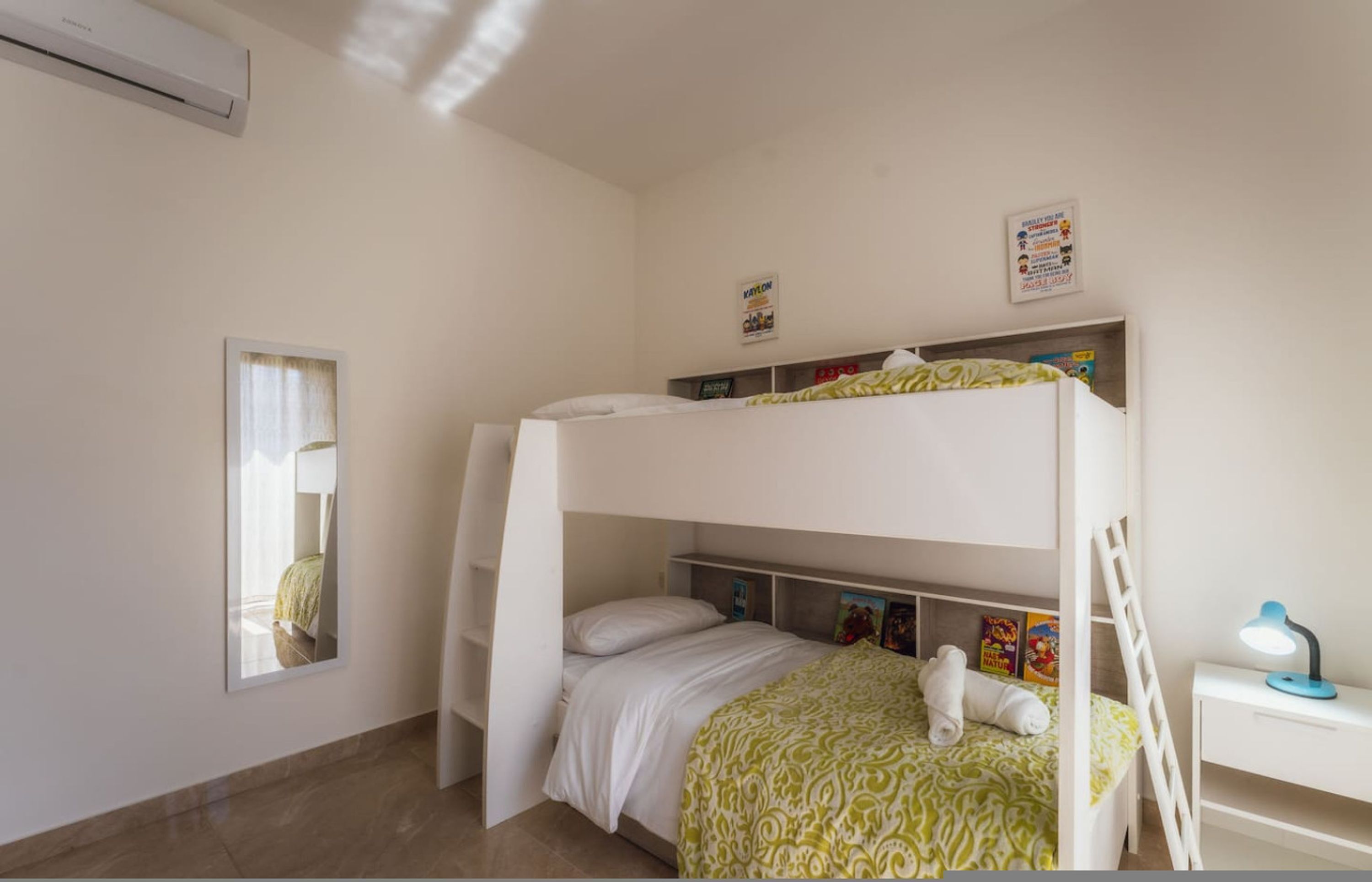 A bunk bed room with a desk, a window with curtains, and a wall-mounted air conditioner.