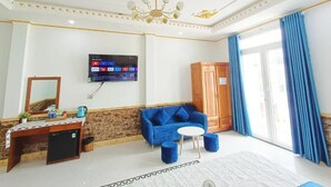 Une chambre d’hôtel équipée d’une télévision, d’un canapé, d’une armoire en bois et d’un tapis à motifs.