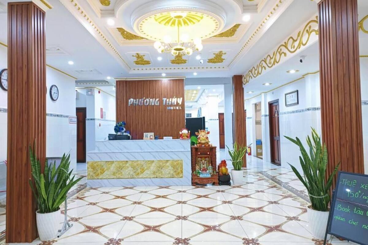 A hotel reception area with a marble floor, wooden reception desk, and a chandelier.