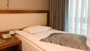 A hotel room with a bed, a bedside telephone, and a window with curtains. - 2017 Hotel (Ankara)