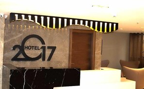 Una reception hotel con un bancone in marmo e un cartello con la scritta 'HOTEL 17'.