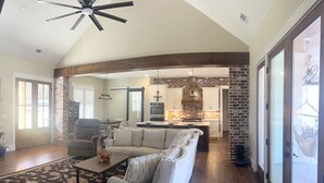 A spacious living area with a large sofa, a coffee table, and a ceiling fan.