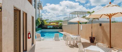 Un espace aménagé au bord de la piscine, avec des chaises longues, une table et des parasols.