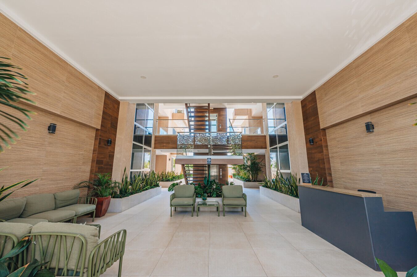 A spacious lobby with a central staircase, seating area, and potted plants.