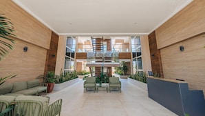A spacious lobby with a central staircase, seating area, and potted plants. - LUX 2BR Condo in Palm Beach | Aracari 7 by Bocobay (Noord)