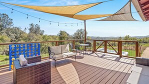 Eine Holzterrasse mit Gartenmöbeln, einem schattigen Bereich und herrlicher Aussicht.