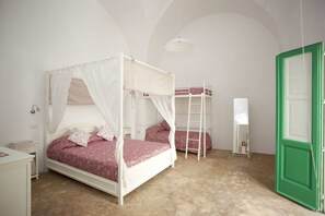 Ein Schlafzimmer mit Baldachinbett, Etagenbett, einer Stehleiter, einem Nachttisch und einer grünen Tür.