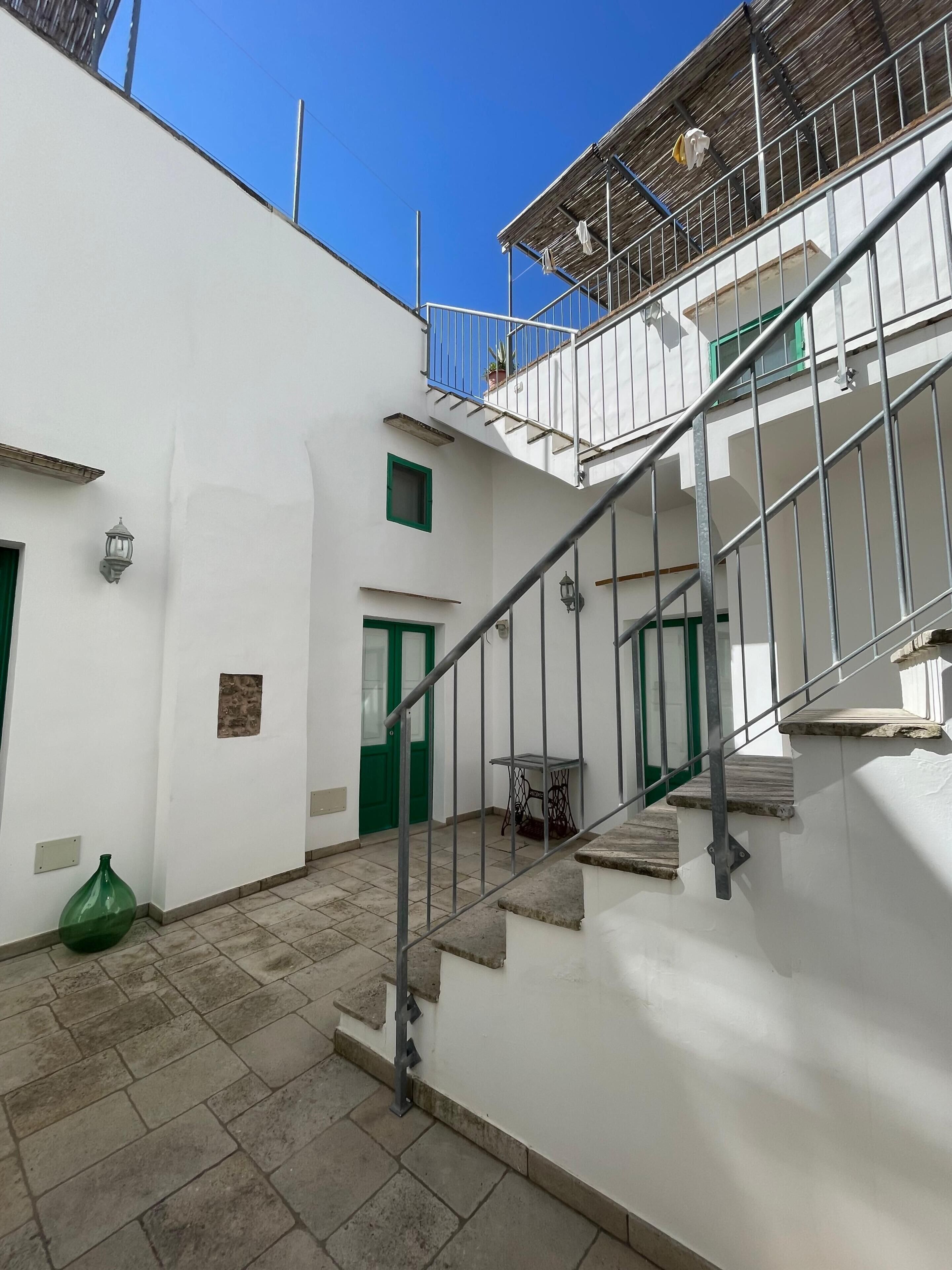 Un edificio bianco con una scala che conduce a un balcone.