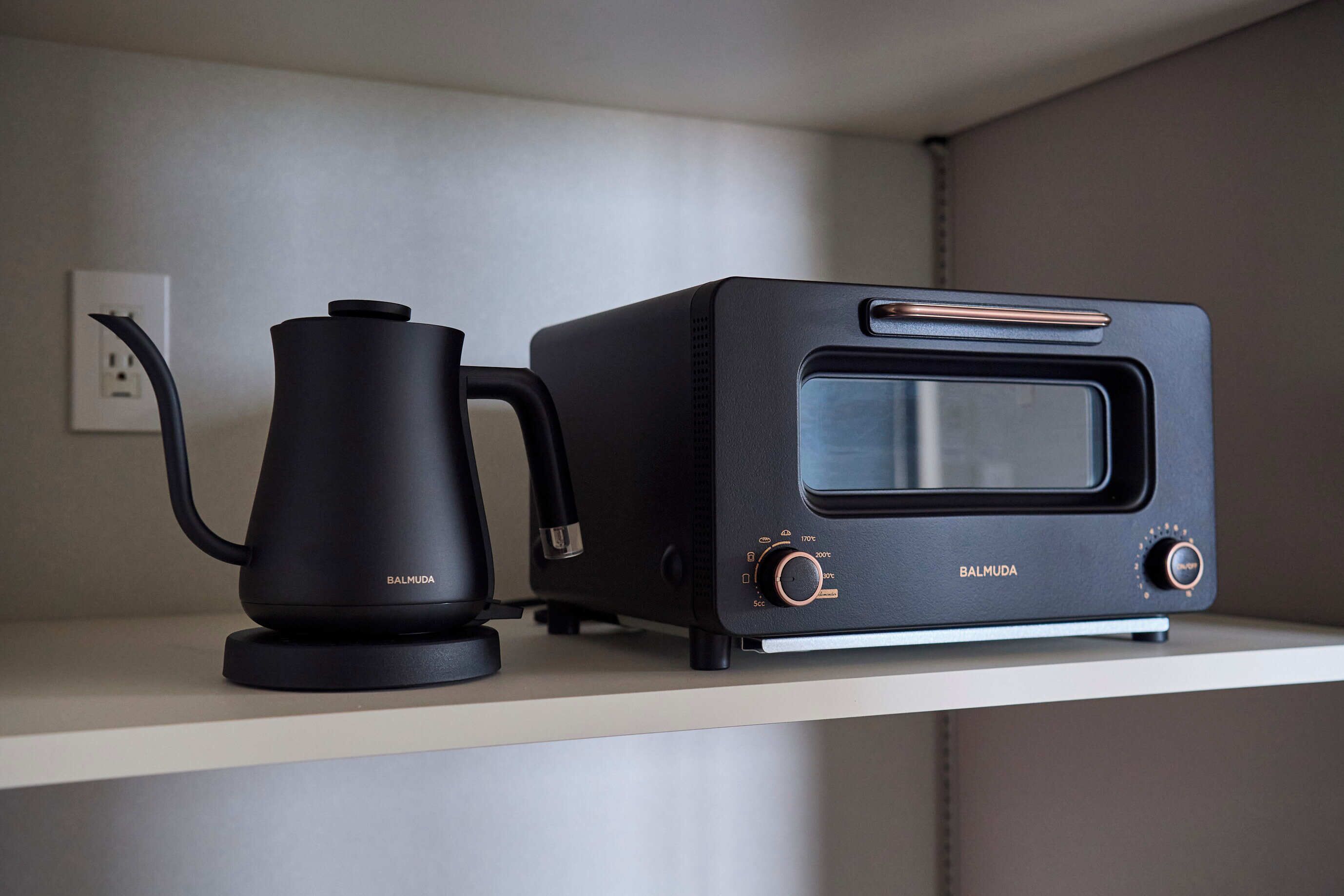Una cocina con cafetera y tostadora sobre un estante blanco.