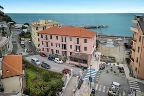 A coastal building with a red roof, a street with parked cars, and a view of the sea. - Amiadò Apartment with Sea View Balcony, Lavagna, Italy (Lavagna)