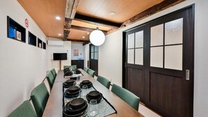 Een lange eettafel met stoelen, een televisie en een groot raam met uitzicht.