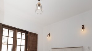 Un dormitorio con cama, suelo de madera y puerta con paneles de vidrio.
