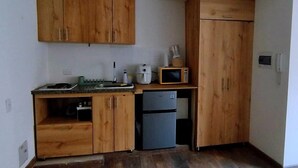 Eine kleine Küche mit Holzausstattung, einer Mikrowelle, einem Kühlschrank und einem Spülbecken.