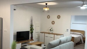 Ein modernes Wohnzimmer mit Sofa, Fernseher, Esstisch und dekorativen Wandbildern.