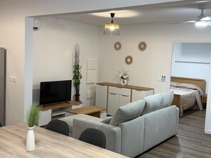 Een moderne woonkamer met een bank, televisie, eettafel en decoratieve muurkunst.