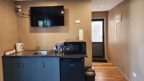 A compact kitchen with a microwave, toaster, kettle, and sink.