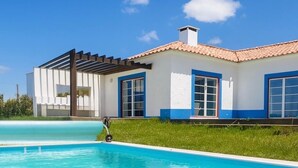 Una casa moderna con piscina, detalles en azul y cielo azul despejado.